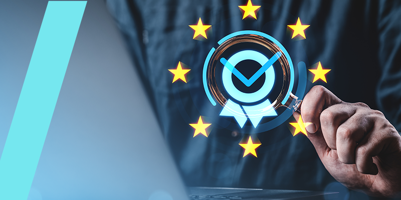 Person’s hand holds a holographic certification badge with a blue checkmark, surrounded by yellow EU stars, over a laptop screen—symbolizing EU compliance and security.
